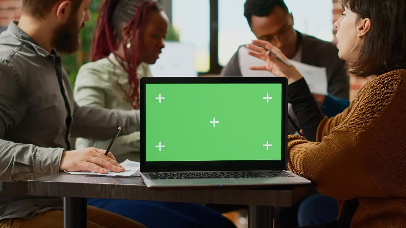 Geschäftsleute arbeiten mit Unterlagen und einem Laptop mit Greenscreen und planen eine Zusammenarbeit. Sie verwenden eine leere Mockup-Vorlage mit Chroma-Key-Display und Copyspace-Hintergrund. Nahaufnahme.